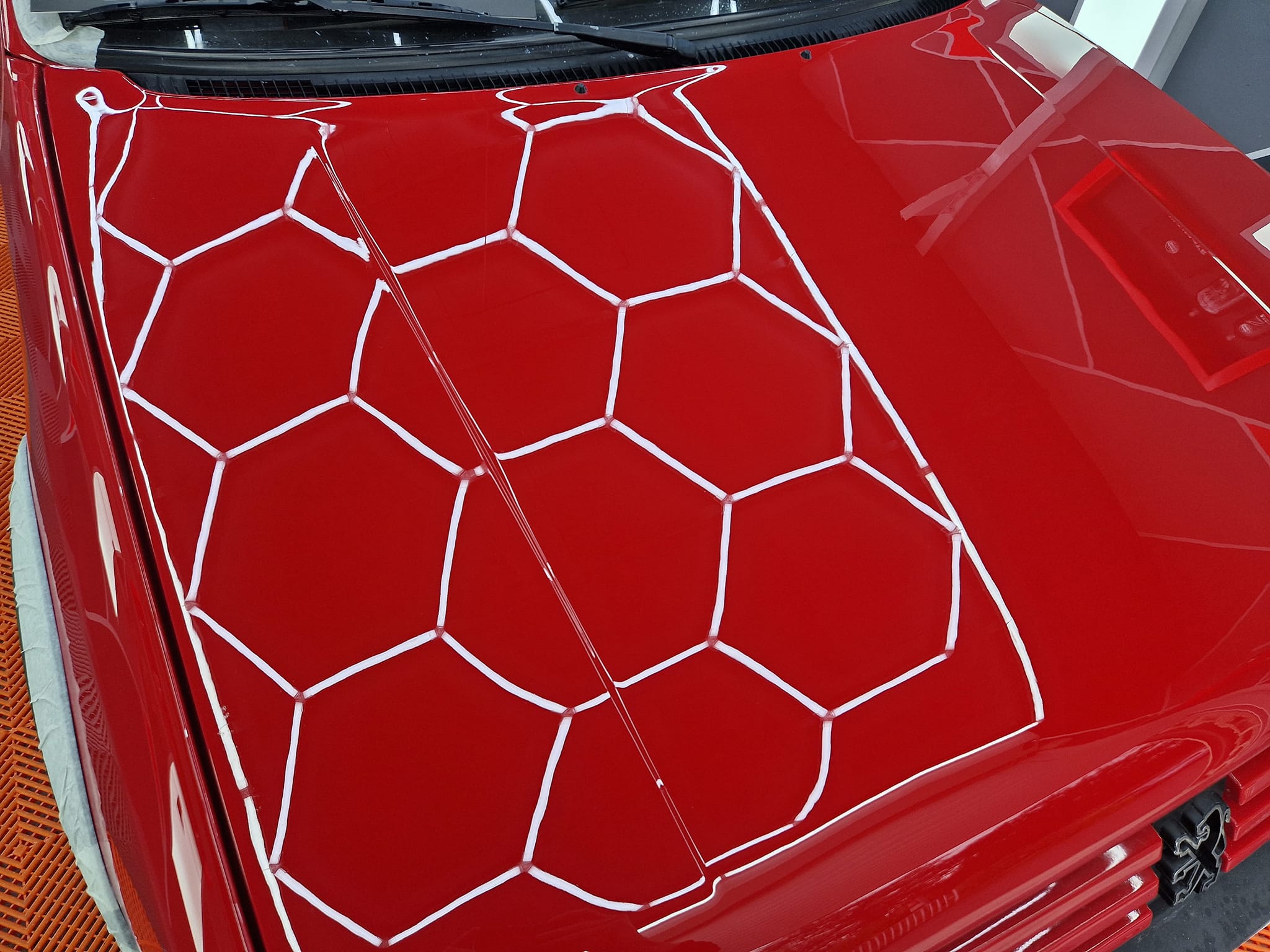 205 GTI — capot rouge reflétant la grille hexagonale de contrôle qualité